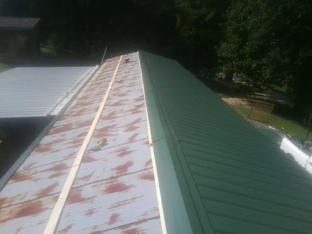 Old rusted panels beside newly installed green metal roofing — Wind Damage Roof Repair by Roofing Brothers in Rockfield
