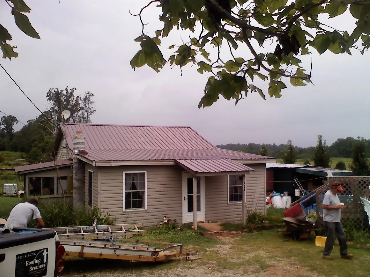 Crew finishing a mauve metal roof on a small farmhouse in Rockfield