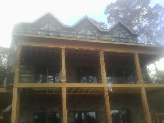 Dormers and porch framing on a large log home under construction — Roof Coating work by our crew in Rockfield