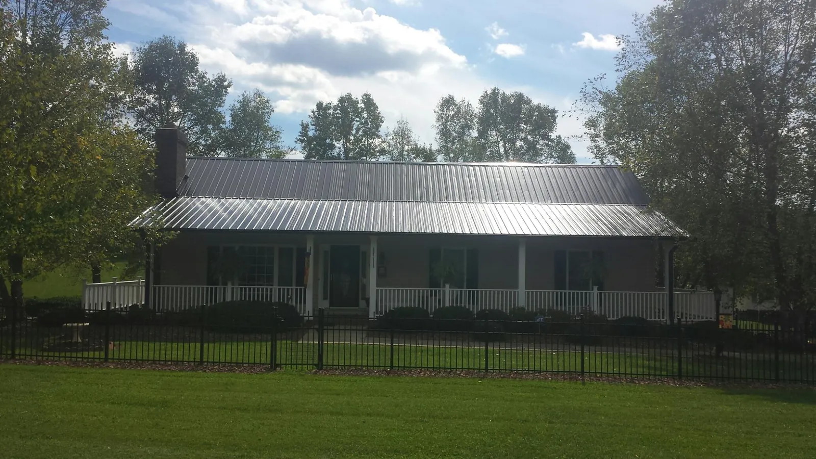 Gray metal roof on a brick ranch with a full width front porch — Gutter Guard Installation work by our crew in Rockfield
