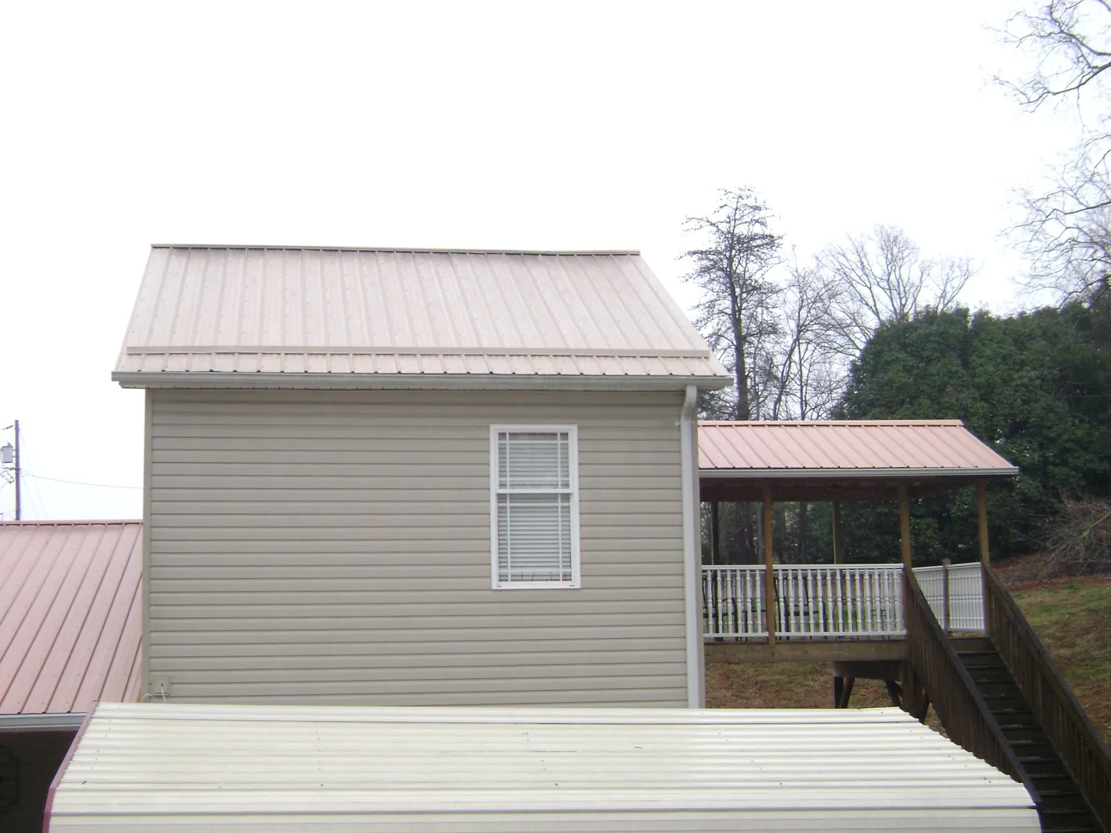Tan metal roofs on a two story addition and attached porch, from a Roof Replacement job in Rockfield