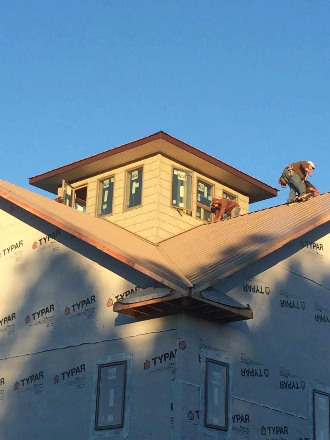 Roofers working around a rooftop cupola on a new metal roof at sunset — Roof Waterproofing in Rockfield by Roofing Brothers